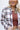 Close up view of model wearing the Harvest Dreams Flannel which features brown, black and cream fabric with a plaid pattern, a button-up front with tortoise buttons, one pocket on the left chest, a collared neckline, a high-low hemline with small slits, a