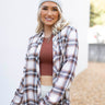 Close up view of model wearing the Harvest Dreams Flannel which features brown, black and cream fabric with a plaid pattern, a button-up front with tortoise buttons, one pocket on the left chest, a collared neckline, a high-low hemline with small slits, a