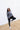 Full body view of model wearing the Greater Days Sweatshirt which features grey fabric, distressed detailing with front zip up, one pocket, a cropped waist, a high neckline, and long sleeves with distressed wrists.