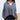 Close up view of model wearing the Greater Days Sweatshirt which features grey fabric, distressed detailing with front zip up, one pocket, a cropped waist, a high neckline, and long sleeves with distressed wrists.