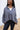 Close up view of model wearing the Greater Days Sweatshirt which features grey fabric, distressed detailing with front zip up, one pocket, a cropped waist, a high neckline, and long sleeves with distressed wrists.