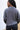 Back view of model wearing the Greater Days Sweatshirt which features grey fabric, distressed detailing with front zip up, one pocket, a cropped waist, a high neckline, and long sleeves with distressed wrists.