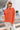 Full body view of model wearing the Breezy Top In Orange which features orange fabric, silver button clasps, collared neckline, distressed hemline and details, dropped shoulder and long sleeves.