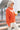 Side view of model wearing the Breezy Top In Orange which features orange fabric, silver button clasps, collared neckline, distressed hemline and details, dropped shoulder and long sleeves.