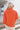 Back view of model wearing the Breezy Top In Orange which features orange fabric, silver button clasps, collared neckline, distressed hemline and details, dropped shoulder and long sleeves.