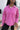 Close up view of model wearing the Breezy Top In Magenta features magenta washed fabric, silver button clasps, collared neckline, distressed hemline and details, dropped shoulder and long sleeves.