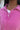 Close up view of model wearing the Breezy Top In Magenta features magenta washed fabric, silver button clasps, collared neckline, distressed hemline and details, dropped shoulder and long sleeves.