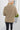 Back view of model wearing the Just Relax Top In Olive which features green fabric, a round neckline, and balloon long sleeves.