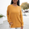 Close up view of model wearing the Fireside Feels Sweater which features honey fabric, a high-low hemline, one pocket on the left chest, a round neckline, and long sleeves.