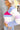 Side view of Whitney Color-Block Sweater which features pink, white, blue, purple and orange ribbed stripe fabric, a cropped waist, a square neckline, and long sleeves.