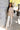 Full body view of model wearing the Fireside Feels Sweater in Beige which features beige fabric, a high-low hemline, one pocket on the left chest, a round neckline, and long sleeves.