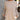 Close up view of model wearing the Fireside Feels Sweater in Beige which features beige fabric, a high-low hemline, one pocket on the left chest, a round neckline, and long sleeves.