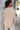 Back view of model wearing the Fireside Feels Sweater in Beige which features beige fabric, a high-low hemline, one pocket on the left chest, a round neckline, and long sleeves.