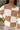 Cllose up view of model wearing the Check This Out Sweater which features white and camel knit fabric with a checkered pattern, a round neckline, a cropped waist and long sleeves.