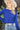 Close up view of model wearing the Talk About It Sweater which features royal blue ribbed knit fabric, a cropped waist, a round neckline and balloon sleeves with cuffed wrists.