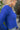 Side view of model wearing the Talk About It Sweater which features royal blue ribbed knit fabric, a cropped waist, a round neckline and balloon sleeves with cuffed wrists.