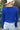 Back view of model wearing the Talk About It Sweater which features royal blue ribbed knit fabric, a cropped waist, a round neckline and balloon sleeves with cuffed wrists.