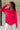 Close up view of model wearing the Up All Night Satin Top which features hot pink satin fabric, monochromatic button up, collared neckline, high-low hem and long sleeves with button closure cuffs.