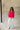 Full body view of model wearing the Up All Night Satin Top which features hot pink satin fabric, monochromatic button up, collared neckline, high-low hem and long sleeves with button closure cuffs.
