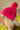 Side view of model wearing the Fireside Beanie in Pink, that features pink knit fabric, a folded cuff with a brown "C.C" patch, and a pink pompom.
