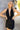 Close up view of model wearing the Skylar Satin Dress in Black which features black satin fabric, halter neckline with a tie, ruching on the sides, back zipper with hook closures and lining.