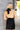 Close up back view of model wearing the Skylar Satin Dress in Black which features black satin fabric, halter neckline with a tie, ruching on the sides, back zipper with hook closures and lining.