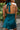 Close up back view of model wearing the Skylar Satin Dress in Teal which features teal satin fabric, halter neckline with a tie, ruching on the sides, back zipper with hook closures and lining.