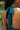 Close up back view of model wearing the Skylar Satin Dress in Teal which features teal satin fabric, halter neckline with a tie, ruching on the sides, back zipper with hook closures and lining.
