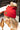 Side view of model wearing the Anchorage Beanie in Red, that has red knit fabric with a stitched pattern, a front patch that says "C.C exclusives", and a brown faux-fur pompom.
