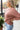 Side view of model wearing the Just Relax Top In Marsala features brown fabric, a round neckline, and balloon long sleeves.