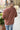 Close up back view of model wearing the Just Relax Top In Marsala features brown fabric, a round neckline, and balloon long sleeves.