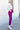 Full body side view of model wearing the Be Fearless Pants, that have magenta corduroy fabric, two front pockets, a paperbag waist with a tie, a zipper and button closure, and straight legs