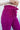 Close upper side view of model wearing the Be Fearless Pants, that have magenta corduroy fabric, two front pockets, a paperbag waist with a tie, a zipper and button closure, and straight legs
