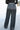 Back view of model wearing the Wish Upon A Star Pants, that have black fabric with metallic silver threads, an elastic band, and flared legs.