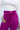 Close upper front view of model wearing the Be Fearless Pants, that have magenta corduroy fabric, two front pockets, a paperbag waist with a tie, a zipper and button closure, and straight legs
