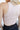 Back view of model wearing the On Repeat Brami in Sand, that features a beige coloring, stretchy-ribbed fabric, a cropped fit, and a high round neckline