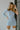 Close up view of model wearing the Making New Rules Dress which features light blue sheen fabric, one shoulder with a long sleeve, lining and ruched detailing along the sides.