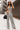 Full body front view of model wearing the Going Rogue Top, which an ivory and black geometric print with a slight sheen, a deep V surplice neck, a thick straps, a cropped fit, and a side zipper closure. Worn with matching pants.