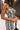 Close-up side view of model wearing the Going Rogue Top, which an ivory and black geometric print with a slight sheen, a deep V surplice neck, a thick straps, a cropped fit, and a side zipper closure. Worn with matching pants.