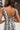 Close-up back view of model wearing the Going Rogue Top, which an ivory and black geometric print with a slight sheen, a deep V surplice neck, a thick straps, a cropped fit, and a side zipper closure. Worn with matching pants.