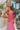 Side view of the Pink Dreams Dress that features a monochromatic pink houndstooth pattern, a cowl neckline, a sleeveless design with thin adjustable straps, and a side slit.
