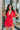 Frontal view of the Speechless Romper that features a red chiffon material, a surplice neckline, a short sleeve with a slit, a waist tie detail, a faux wrap skirt overlay, a shorts back, and a back zipper closure.