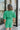 Frontal view of the Speechless Romper that features a green chiffon material, a surplice neckline, a short sleeve with a slit, a waist tie detail, a faux wrap skirt overlay, a shorts back, and a back zipper closure.