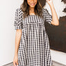 Front view of model wearing the Go Your Own Way Dress, which has a black and ivory plaid pattern, a straight neckline, a puffy half sleeve, pockets, a back zipper closure, and a mini length