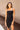 Front view of model wearing the Show Stopper Dress in Black, which features a black chiffon material, a straight neckline, a sleeveless design with thin straps, and a ruched overlapped detail on the skirt