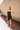 Full body front view of model wearing the Show Stopper Dress in Black, which features a black chiffon material, a straight neckline, a sleeveless design with thin straps, and a ruched overlapped detail on the skirt