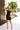 Full body front view of model wearing the Always A Classic Dress, which features a black chiffon material, a straight neckline, a sleeveless design with a one shoulder thin strap, a twisted knot detail at the waist, and a mini length