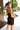 Back view of model wearing the Always A Classic Dress, which features a black chiffon material, a straight neckline, a sleeveless design with a one shoulder thin strap, a twisted knot detail at the waist, and a mini length
