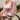 Close-up view of model wearing the Lost In A Daydream Dress, which features a blush colored material, a white and orange floral print, a V neckline, a long sheer sleeve with smocked detailing at the wrist, a ruffle detail at the bottom