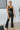 Front view of model wearing the Daily Ritual Faded Jeans, which have a stretchy denim material, a faded black wash, a flare leg fit, a high-rise waist, a five button closure, two front pockets, a frayed/distressed flare hem, and two back pockets
